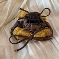 Vue macro d'une pince à cheveux à nœud en velours marron et jaune sur tissu beige - Pince Plissée Nœud Jaune Velours Café