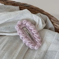 Dettaglio di un fermaglio per capelli rosa lavorato a maglia con lana e base in metallo - Rosa
