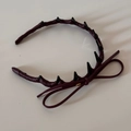 Close-up of a burgundy leather headband with black spiky decor and a slim ribbon bow - Burgundy Leather Bow Headband