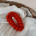 Dettaglio di un fermaglio per capelli in lana all'uncinetto color terracotta caldo - Arancione