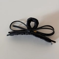 Detail of matte black leather bow hair claw clip featuring a gold Love metal plaque - Black Leather Bow Claw