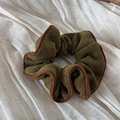 Nahaufnahme eines Retro-Grün-Strick-Haargummis mit brauner Paspelierung auf Leinen - Eingefasster Scrunchie