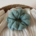 Dettaglio ravvicinato di un elastico per capelli in maglia blu in un cesto di vimini - Verde
