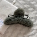 Dettaglio di un fermaglio per capelli in ecopelliccia grigia con un fiocco di nastro nero - Verde
