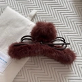 Détail d'une pince à cheveux en peluche bordeaux avec pompons en fourrure et nœud en cuir - Rouge