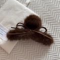Détail d'une grande pince à cheveux marron en peluche avec nœud sur un tissu en maille - Marron