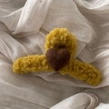 Close-up of yellow plush shark hair clip with a brown wool felt heart on fabric - Yellow