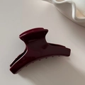 Detailed top view of a glossy burgundy acetate hair claw clip on a minimalist surface - Red