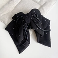 Dettaglio della pinza per capelli a fiocco nero con perline e paillettes argento - Stile nappa