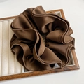 Close-up of chocolate brown satin hair scrunchie with elegant folds on a wooden tray - Brown