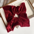 Macro view of large red velvet scrunchie with bow detail and gold bead in a jewelry box - Red