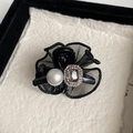Détail d'une pince à fleur en maille noire élégante avec cristal et perle nacrée - Noir (Design Strass & Perles Artificielles)