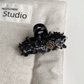 Detail van tweed haarklem met gouden camelliabloem en strass-steentjes - Zwarte Haarklem