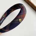 Détail du bandeau à carreaux épais avec motif vintage et un logo rond en métal doré - Serre-Tête À Carreaux Marine