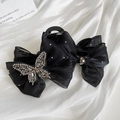 Dettaglio del fermaglio per capelli in tulle nero con fiocco e farfalla di cristallo - Stile a Doppio Fiocco