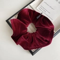 Detail of burgundy velvet scrunchie with ruffled texture and premium glossy sheen - Red