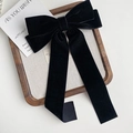 Close-up of elegant black velvet bow hair clip with long ribbons on a wooden tray - Black