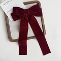 Detail of a large dark red velvet bow hair clip with long ribbons in a wooden tray - Red