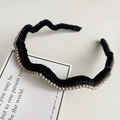 Detailed view of black wavy velvet headband with pearl edge embellishments on fabric - Black