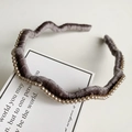Detail view of a wavy grey velvet headband with hand-sewn pearls and retro texture - Gray