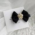 Detailed close-up of a black satin bow hair clip with a pearl camellia and crystal center - Black