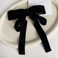 Dettaglio di un grande fiocco di velluto nero con lunghi nastri su un vassoio chic - Stile Piccola Farfalla