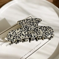 Dettaglio della pinza per capelli in acetato con motivo marmoreo e logo dorato retrò - Pois Nero Bianco