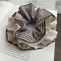 Detail van bruine ruitjes scrunchie met witte kant op een vintage boekpagina - Koffie Geblokt