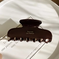 Macro detail of glossy dark acetate hair claw clip with Borrettc La France golden lettering - Chocolate Brown