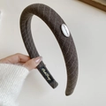 Padded brown headband with diamond knit pattern and oval gold metal logo detail - Brown