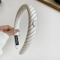 Detailed texture of off-white twill headband with sponge padding and oval metal logo - White