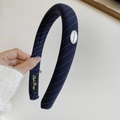 Close-up of navy blue textured headband featuring white diagonal dots and silver oval logo - Navy Blue