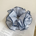 Dettaglio di un elastico per capelli in tessuto a righe bianche e blu su un giornale - Bianco