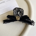 Detail view of tweed hair claw clip with black velvet bow and golden camellia ornament - 13cm / Black