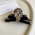 Detailed macro view of tweed hair claw with velvet bow and golden camellia flower accent - 11cm / Brown