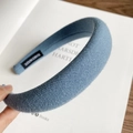 Detailed macro view of light blue knitted headband with handmade label on white book - Blue