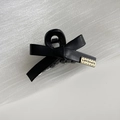 Detailansicht der schwarzen Leder-Schleifen-Haarklammer mit graviertem goldenem Metallemblem - Schwarz