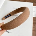Detailed close-up of thick knitted headband with a handmade textile label on the inner side - Khaki
