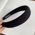 Detail view of handmade black knitted wide headband with soft texture and inner tag - Black