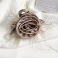 Eleganter champagnerfarbener Rosen-Haarclip aus Seide mit Federn auf weißem Plüschgrund - Champagner