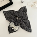 Détail d'un chouchou floral avec nœud en dentelle blanche et pendentif perle élégant - Noir