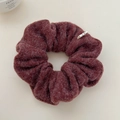 Detailed view of a deep red wool texture scrunchie with a small designer woven label - Red Hair Tie