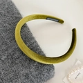 Detail eines olivgrünen Samt-Stirnbands mit handgefertigtem Etikett auf Strick - Grün