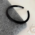 Nahaufnahme eines handgefertigten schwarzen Samt-Stirnbands mit Label auf Strick - Schwarz