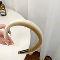 Dettaglio ravvicinato di un cerchietto in velluto color oro champagne con etichetta fatta a mano - Caffè Chiaro