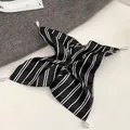 Detail view of a striped satin scrunchie featuring elegant pearl charms and silver settings - Black Striped Scarf