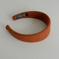 Detail view of handmade caramel wool headband with sponge padding and woven label - Orange