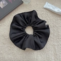 Detailed top view of large black satin scrunchie with high-density pleats on plush background - Black