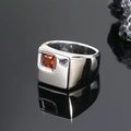 Detalle macro de un anillo cuadrado plateado para hombre con gema roja sobre fondo negro pulido - Talla 7 / Gema rojo naranja color acero