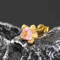Nahaufnahme von rosafarbenem Edelstein-Ohrstecker mit goldener Fassung auf schwarzem Stein - Gold Rosa Zirkonia